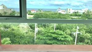 Un bagno con una vasca, una finestra vista verde e edifici, e un soffitto con quattro lampade.