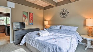 Ein Schlafzimmer mit einem großen Bett, einem Fernseher auf einer Kommode, einer Lampe und Kunstwerken an der Wand.