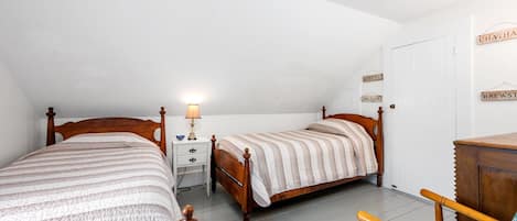 Ein Schlafzimmer mit zwei hölzernen Betten, einem Nachttisch mit Lampe und einem Stuhl.