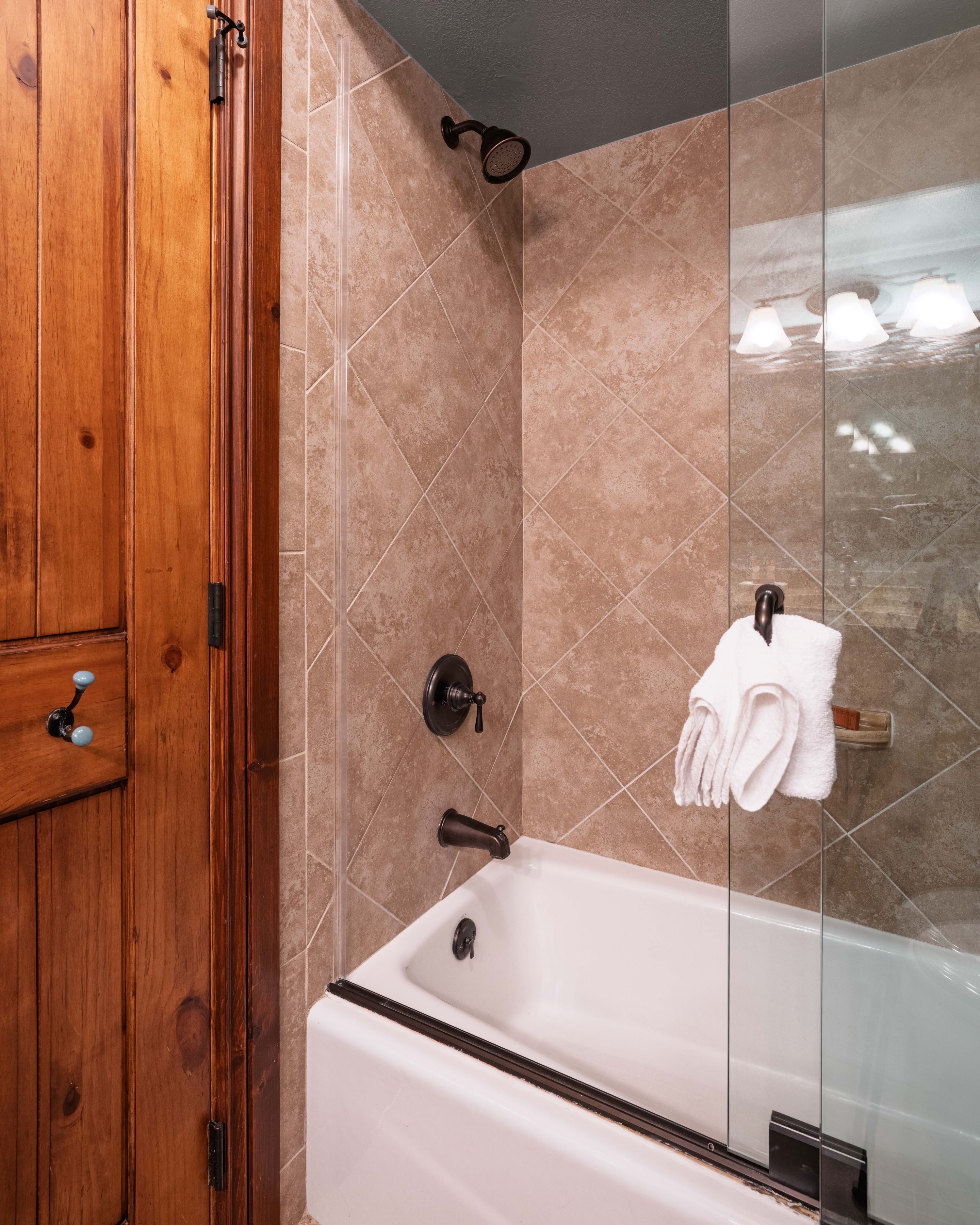 Une salle de bain moderne avec un meuble-lavabo en bois, une douche à parois de verre et une baignoire blanche.