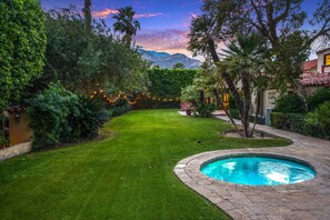 A backyard with a swimming pool, lush greenery, and a mountain view.