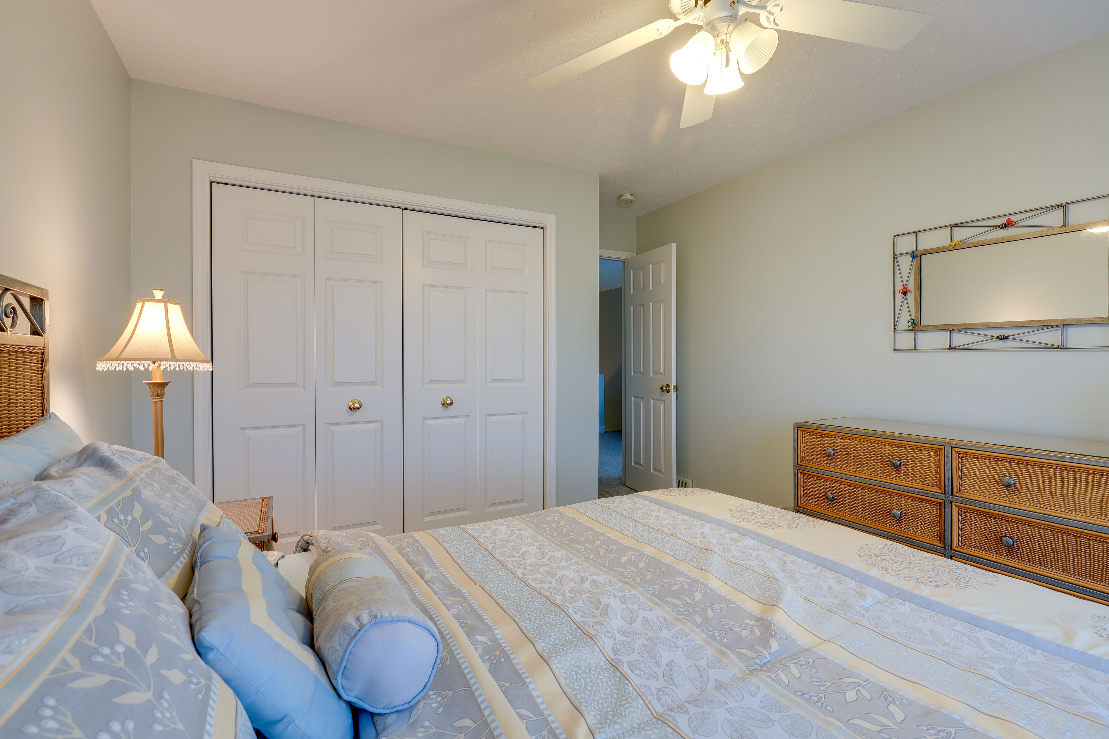 Un dormitorio con cama, cómoda, espejo y puerta.