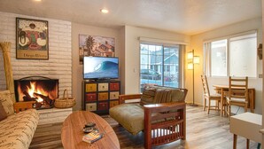 A cozy living room with a fireplace, a television, and a view of the street.