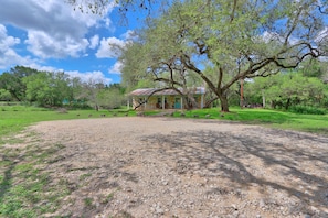 A rustic house with a gravel driveway, surrounded by trees and greenery.