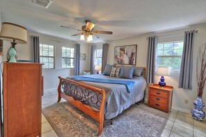 A bedroom with a wooden bed, a ceiling fan, a nightstand, a vase, and a window with curtains. - Your own Private Oasis, pool, hot tub, fire pit on 10 gorgeous acres (Wimberley)