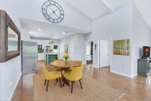 Una cocina amplia con electrodomésticos modernos, un comedor con sillas amarillas y un reloj grande en la pared.
