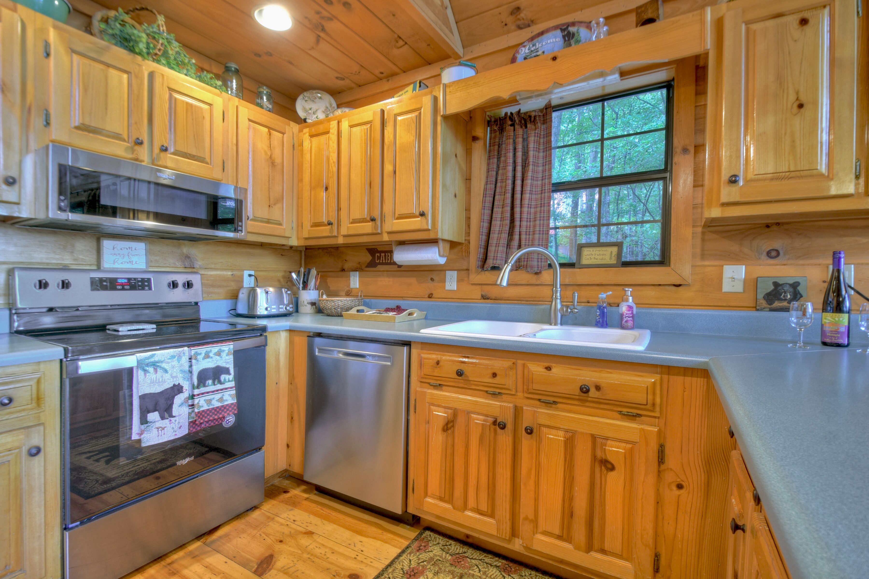 A wooden cabin kitchen with a stainless steel stove, microwave, and dishwasher.