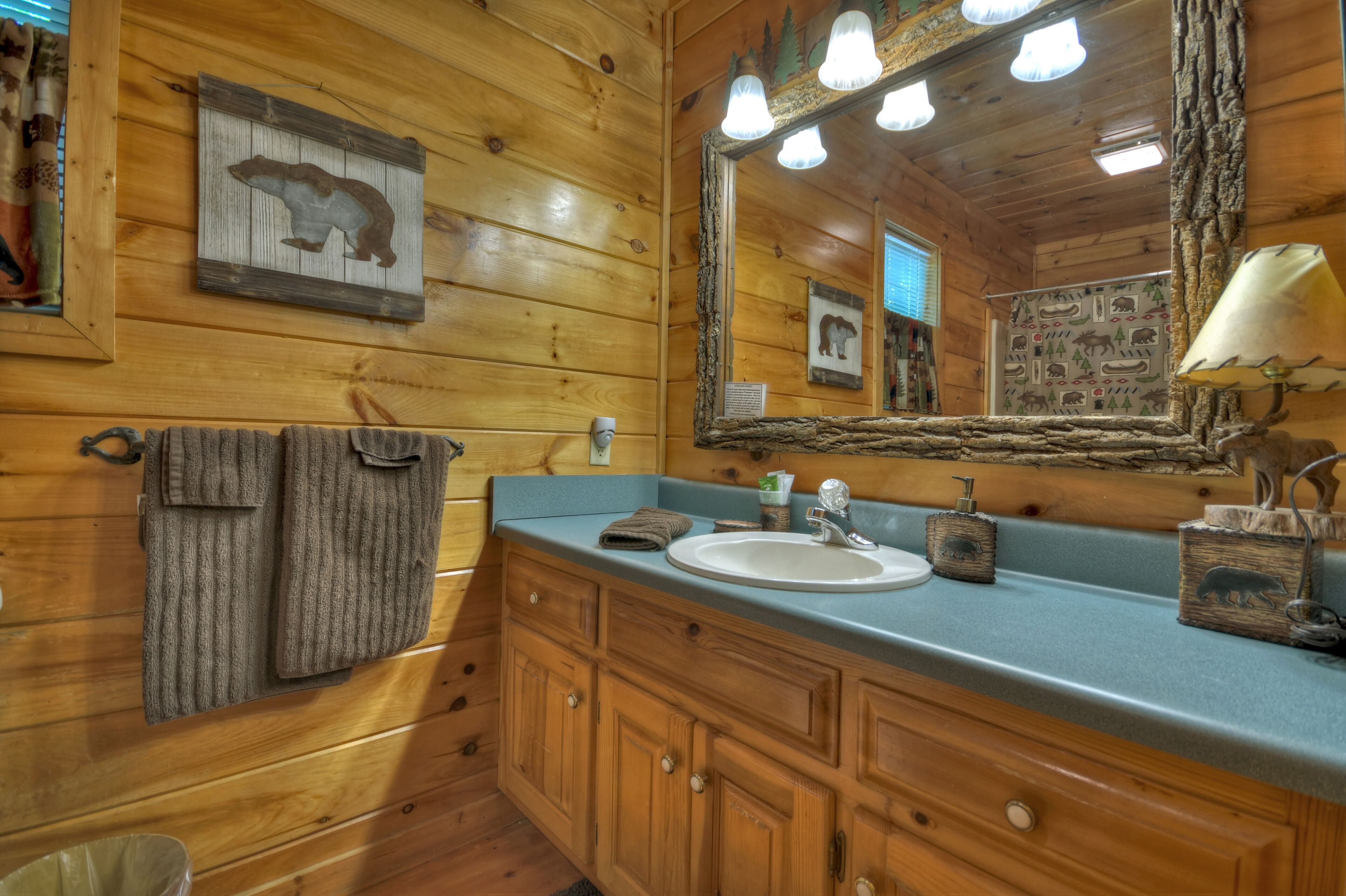 Ein Badezimmer im Chalet-Stil mit Holzeinrichtung, einem Waschtisch und einem Spiegel.