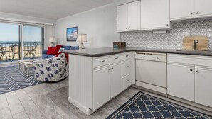 A modern kitchen with white cabinets, a black countertop, and a view of the beach through large windows. - Well maintained 1 BR, 1.5 BA oceanfront condo. Enjoy the beautiful ocean views from your balcony and inside the unit. (Ocean City)