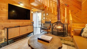 L’intérieur d’un chalet en bois chaleureux et accueillant, avec une télévision, un coin salon et une cheminée.