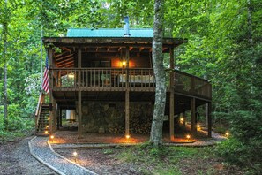 Escape to a secluded cabin surrounded by a forest, featuring a deck, staircase, and chimney.