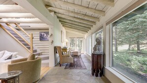 A spacious hallway with a stone floor, a wooden ceiling, and a large window offering a view of the outdoors. - Snowmass Home w/ Hot Tub, Fireplace, & Mtn Views! (Snowmass)