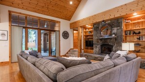 Ein gemütliches Wohnzimmer mit Kamin aus Stein, Holzbalken und einem großen Fenster.