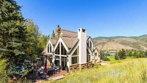 Une grande maison avec des fondations en pierre, de nombreuses fenêtres et une cheminée.