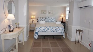 A bedroom with a bed, two bedside tables with lamps, a mirror, and an air conditioning unit. - Pryor Dog Friendly, Huge Porch, Creek Dock (Pawleys Island)