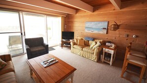 Ein gemütliches Wohnzimmer mit Holzboden, einer Couch, einem Couchtisch und einem Fernseher.