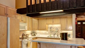 A modern kitchen with wooden cabinets, a central island, stainless steel appliances, and a decorative backsplash. - Stunning Views! Walk to Lifts/Downtown! (Breckenridge)