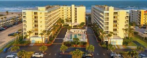 Un hôtel situé en bord de mer, avec plusieurs étages, une cour intérieure dotée d’une piscine et un parking.