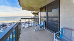 A balcony with a view of the beach, a table, and two chairs. - Charming, unique 2-bedroom oceanfront condo with southwest decor, free WiFi, an indoor and outdoor pool, and more located uptown just steps from the beach! (Ocean City)