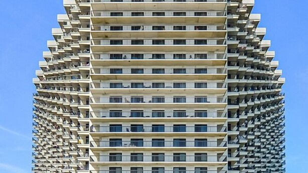 A high-rise building with a unique architectural design, featuring balconies on each floor. - Charming, unique 2-bedroom oceanfront condo with southwest decor, free WiFi, an indoor and outdoor pool, and more located uptown just steps from the beach! (Ocean City)