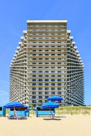A high-rise building with a unique architectural design, featuring balconies on each floor. - Charming, unique 2-bedroom oceanfront condo with southwest decor, free WiFi, an indoor and outdoor pool, and more located uptown just steps from the beach! (Ocean City)