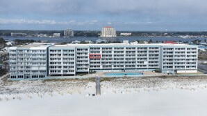 Et hotel ved stranden med flere altaner, en swimmingpool og udsigt over havet og byens skyline.