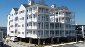 A multi-story building with balconies, a garage, and a stop sign in the foreground. - Unique 5BR, 4.5 bath single floor condominium with great ocean views. (Ocean City)