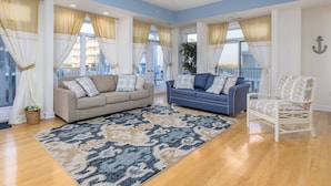 A spacious living room with a blue and beige color scheme, featuring two sofas, a patterned rug, and a ceiling fan. - Unique 5BR, 4.5 bath single floor condominium with great ocean views. (Ocean City)