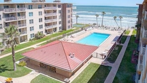 Un hôtel doté d’une piscine, d’un bâtiment au toit rouge et offrant une vue sur l’océan.