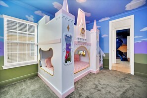 A castle-themed playroom with a bed, a clock, and a door leading to another room.