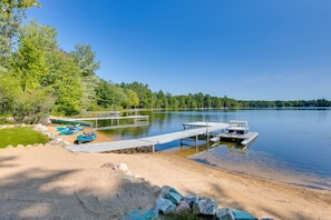 Guests can enjoy access to the lake from the dock, surrounded by a sandy beach and lush greenery.
