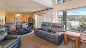 Ein geräumiges Wohnzimmer mit Ledersofas, einem Kamin und Blick auf eine verschneite Landschaft.
