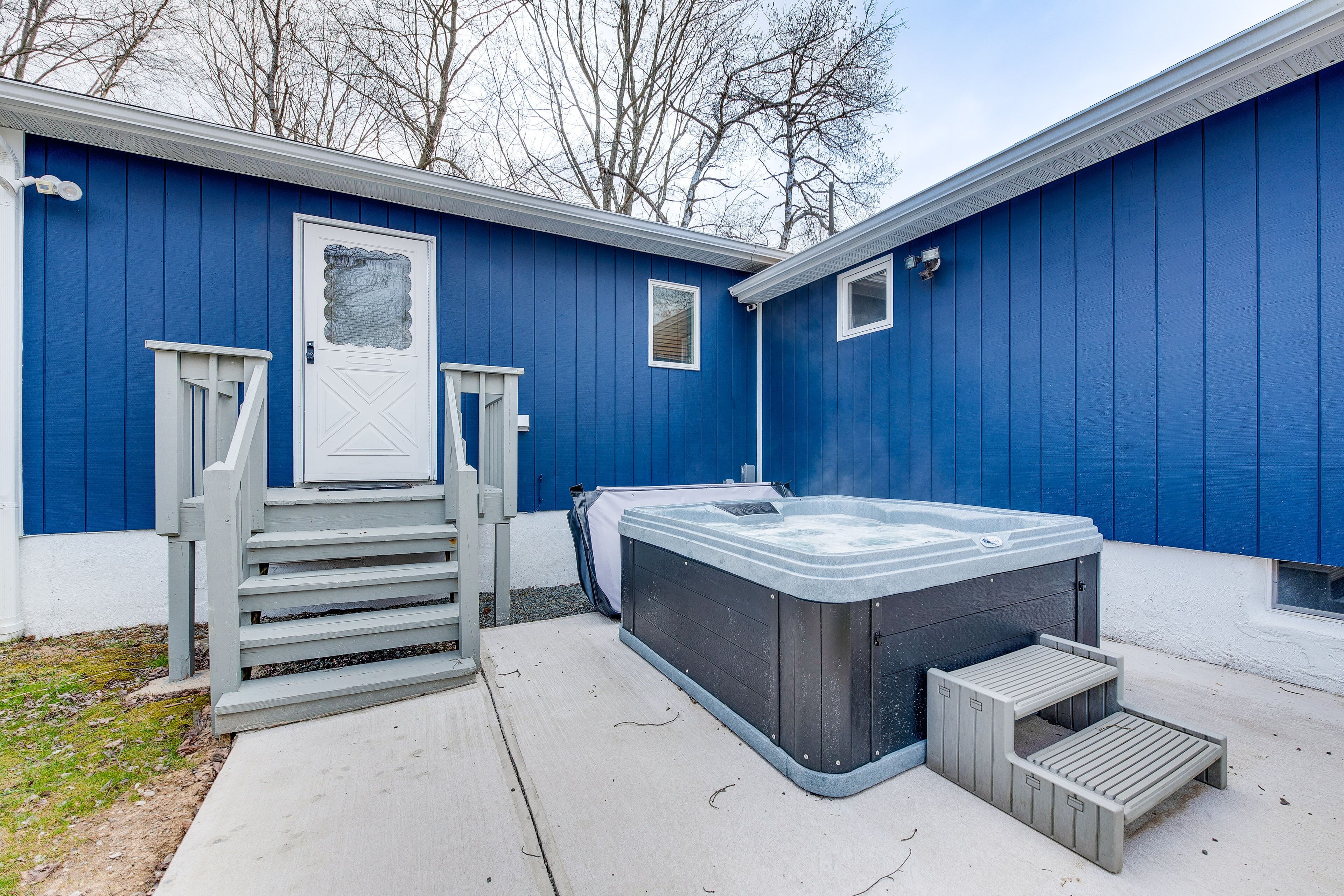 Un bâtiment bleu avec un jacuzzi, une porte et une petite fenêtre.