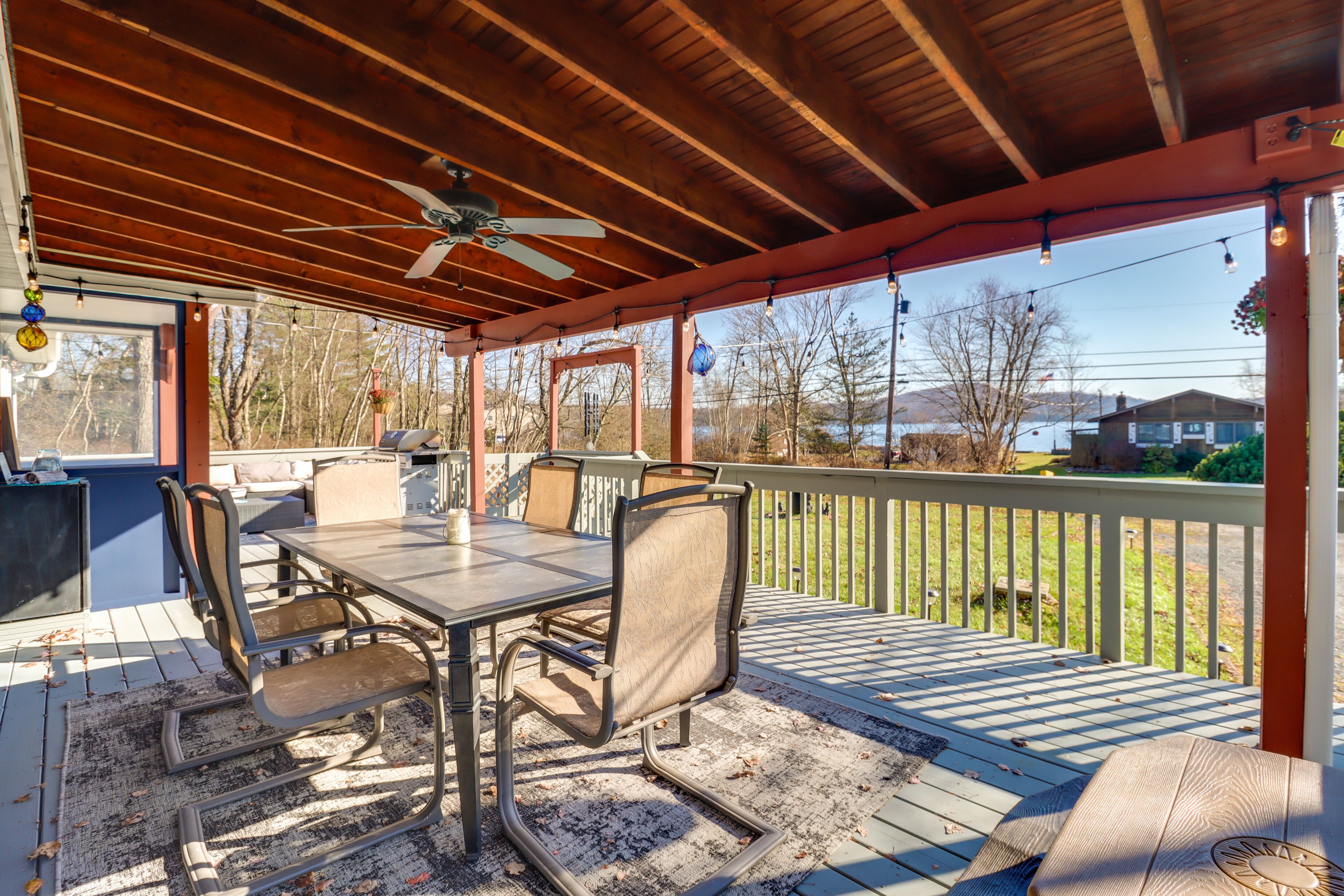 A covered outdoor patio with a table and chairs, a ceiling fan, and a view of the surrounding area.