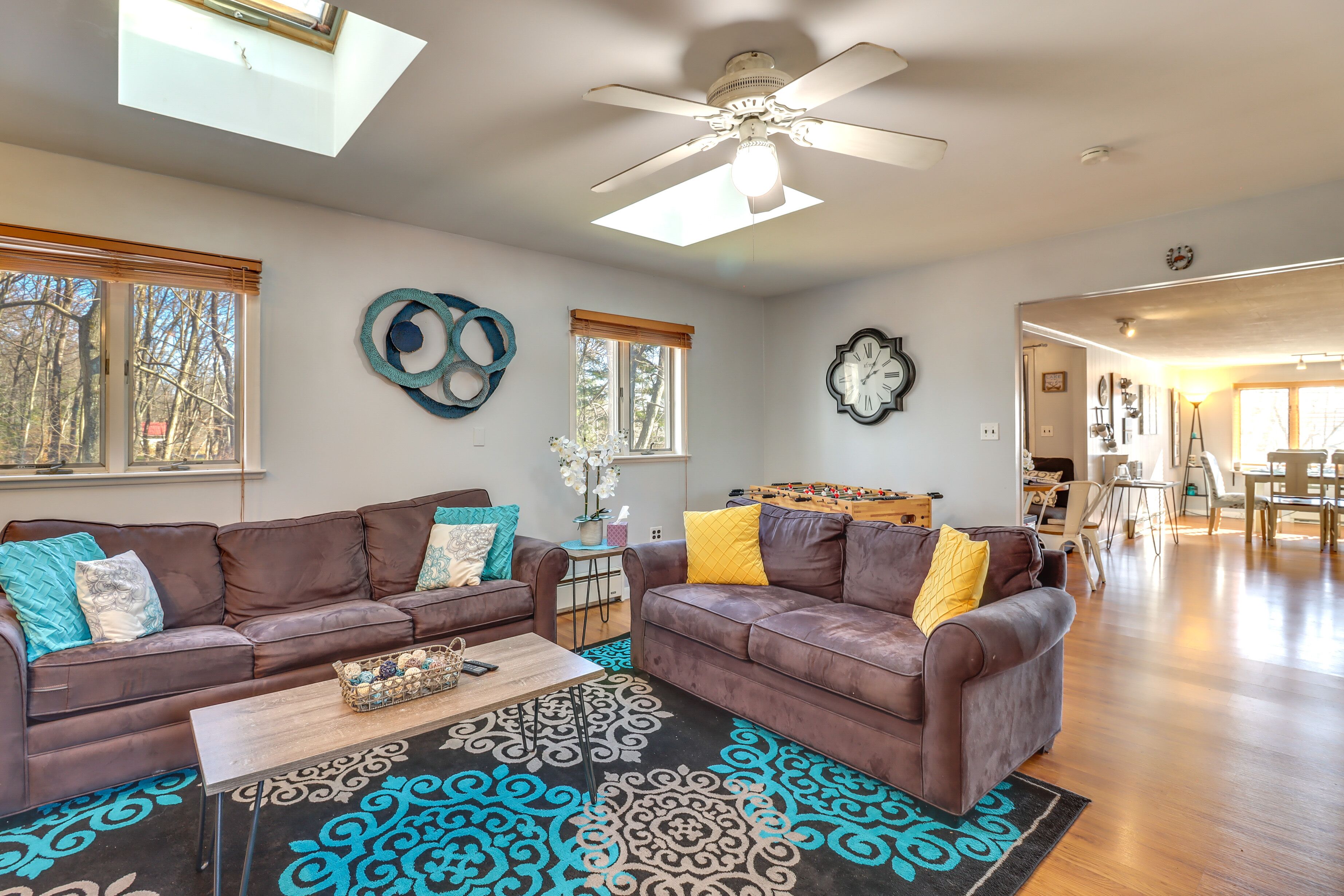 A spacious living room with two brown leather sofas, a wooden coffee table, and a patterned rug.