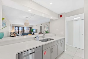 Una cocina moderna con una isla grande, electrodomésticos de acero inoxidable y vistas al área de estar.