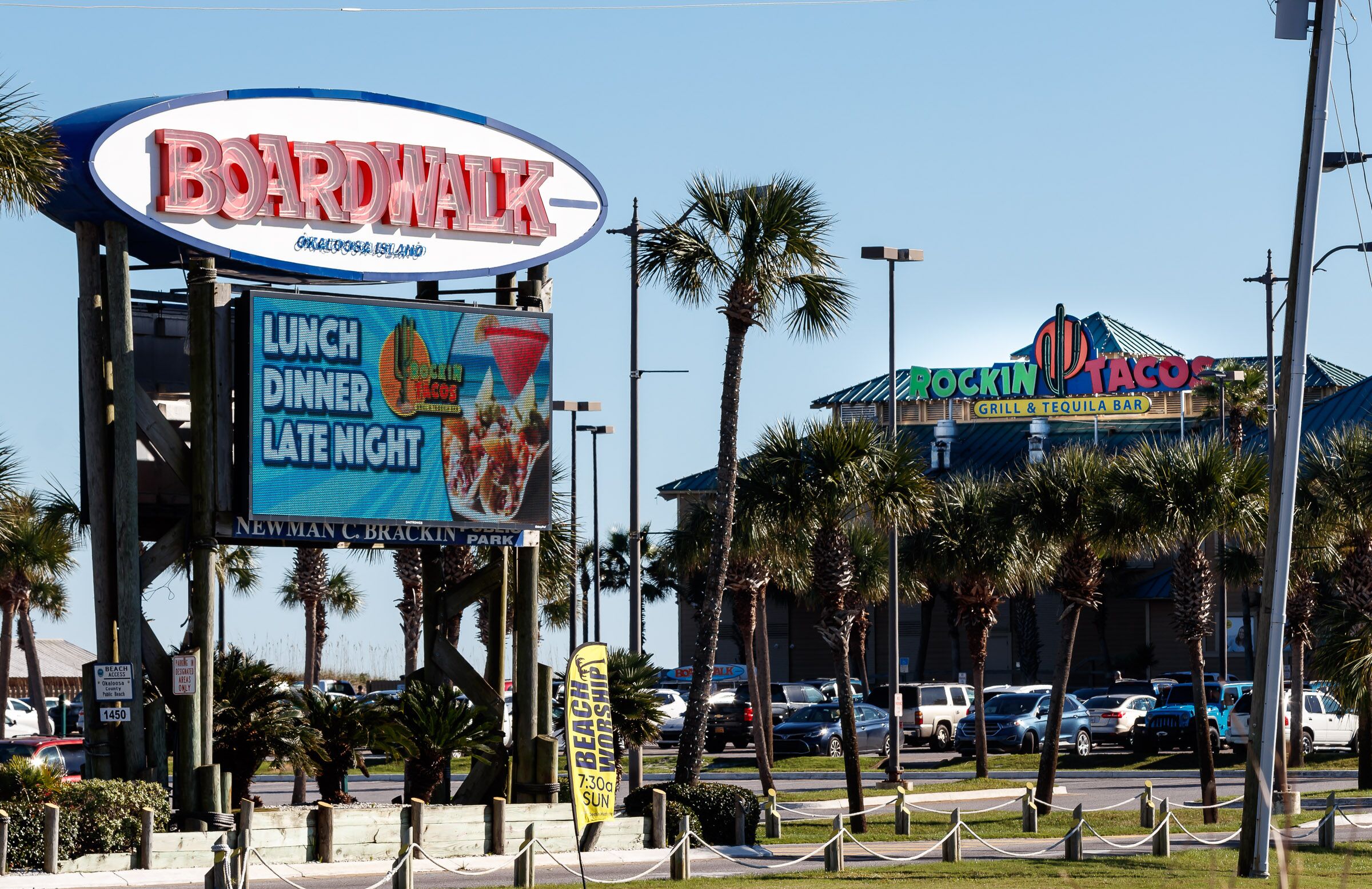 A sign for Boardwalk with a neon sign for Rockin' Tacos in the background.