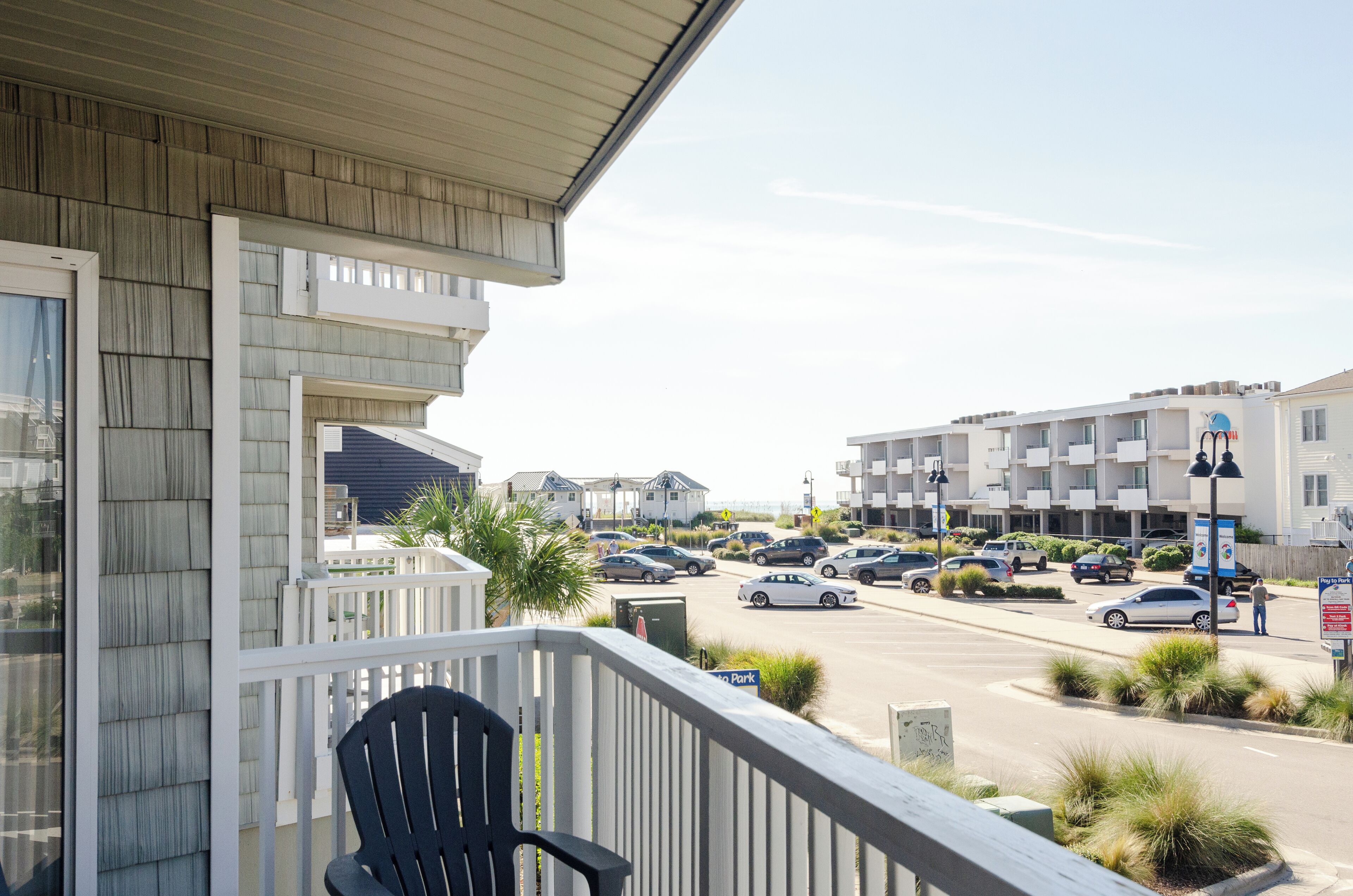 Een motel met balkon, een parkeerplaats en uitzicht op de straat.