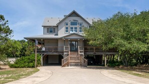 A two-story house with a front porch, a covered front entrance, and a driveway leading to a garage. - Rookery - Corolla, Whalehead, 395 Yds to Beach, Ocean View, Pool, Hot Tub, Pets OK, Flex Stays (Corolla)
