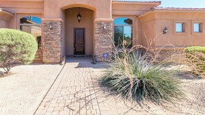 A stucco building with a stone entrance, a door, and a small porch area.