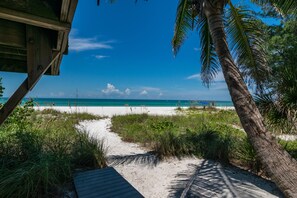 Ein Strandweg, der zum Meer führt, mit einer Holzkonstruktion auf der linken Seite.