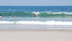 A beach with people swimming and surfing. - Time to Paws & Reflect - Corolla, Ocean Sands, Ocean View, Beach 260 Yds, Pool, Pets OK, Flex Stays (Corolla)