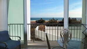 Een balkon met uitzicht op de oceaan, een stoel en een tafel.