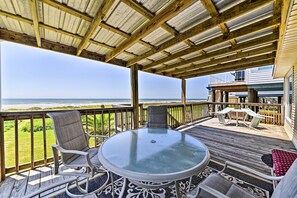 A covered outdoor deck with a glass table and chairs, overlooking the ocean. - Steps to Private Beach! Pet-Friendly Getaway (Galveston)