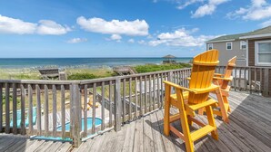 A wooden deck with a pool, chairs, and a view of the ocean.