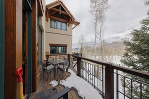 A wooden deck with outdoor furniture, a view of snow-covered mountains, and a building with large windows. - Spacious Luxury Home by InvitedHome | Hike-In/Hike-Out, Village Core (Mountain Village)