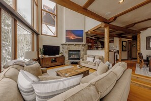 A spacious living room with a fireplace, large windows, and a cozy seating area.