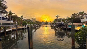 A marina with boats docked, a calm waterway, and a sunset in the background.