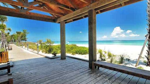 A wooden deck with a view of a beach and ocean.
