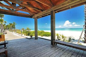 A wooden deck with a view of a beach and ocean.